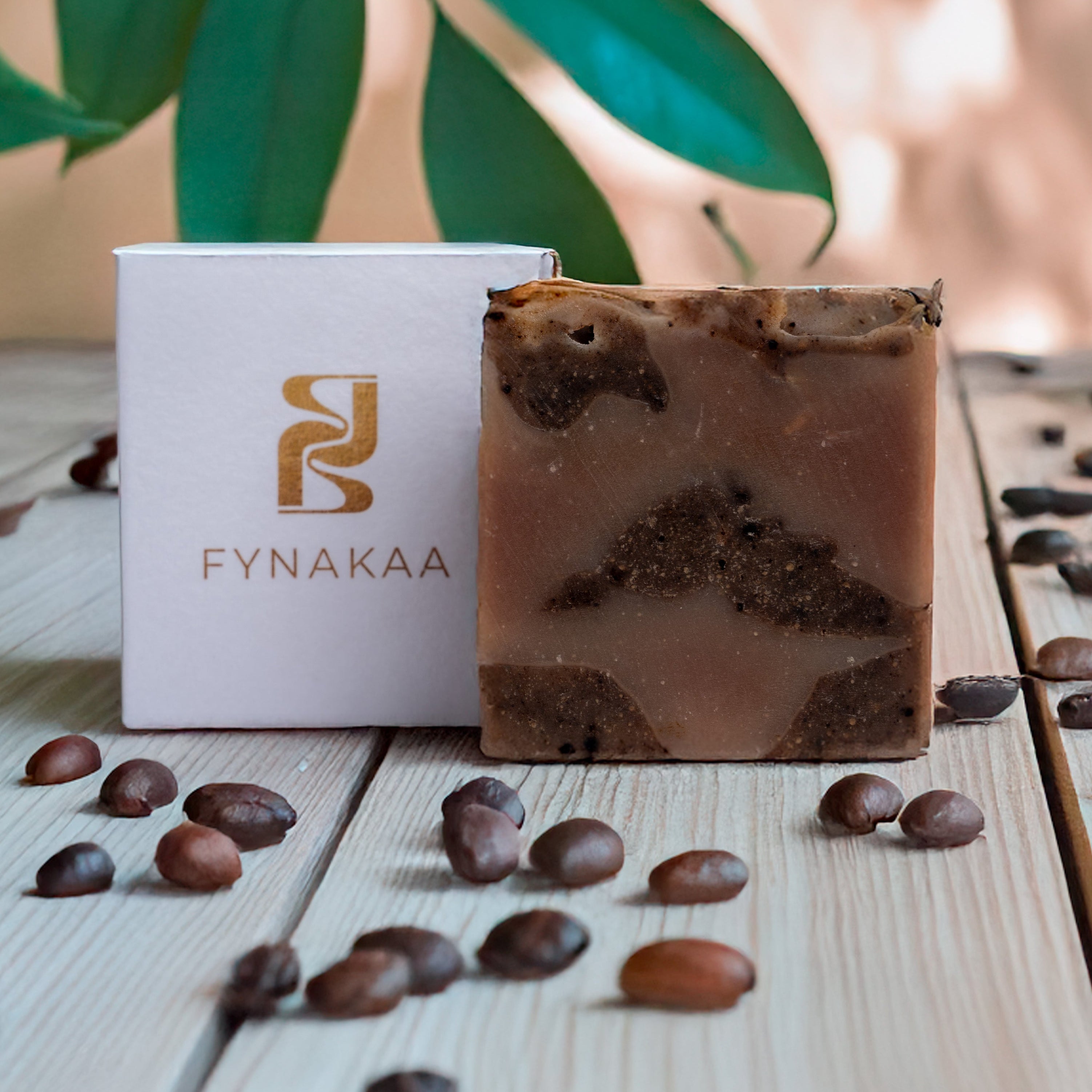 Fynakaa coffee-flavored soap with packaging on a wooden surface with coffee beans.