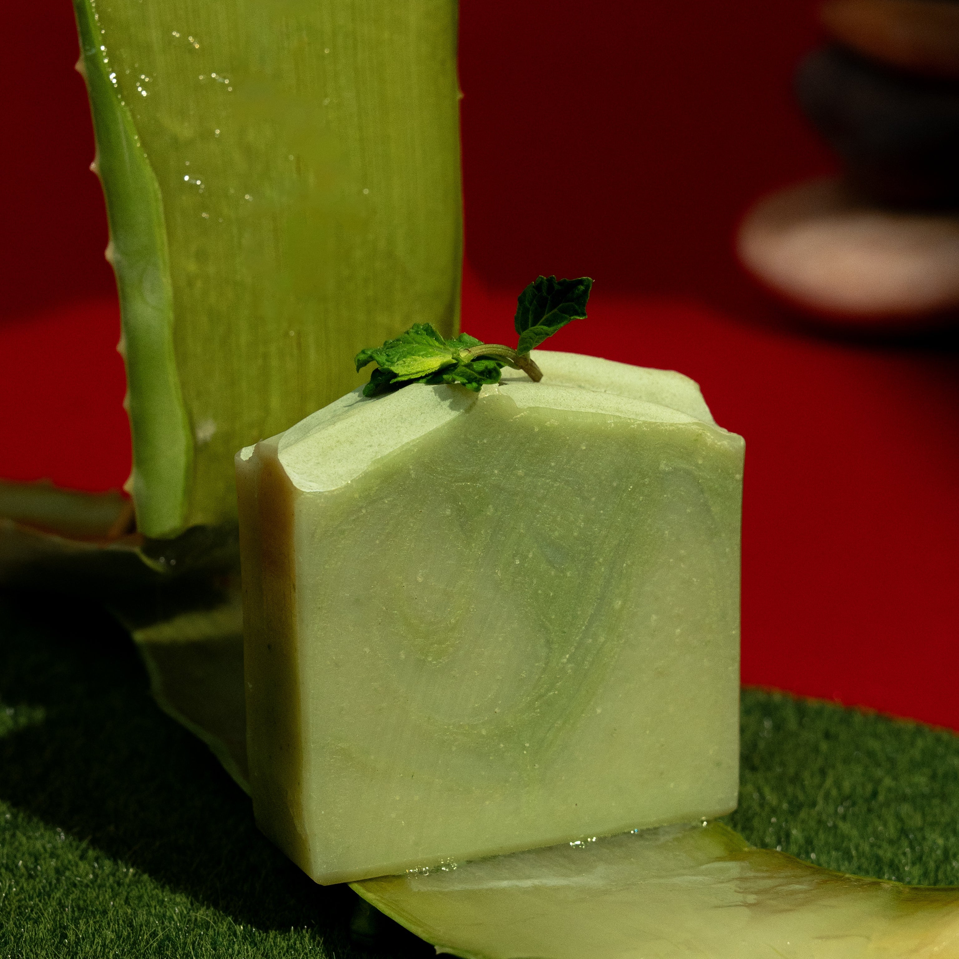 Block of green soap with a slice on a red background