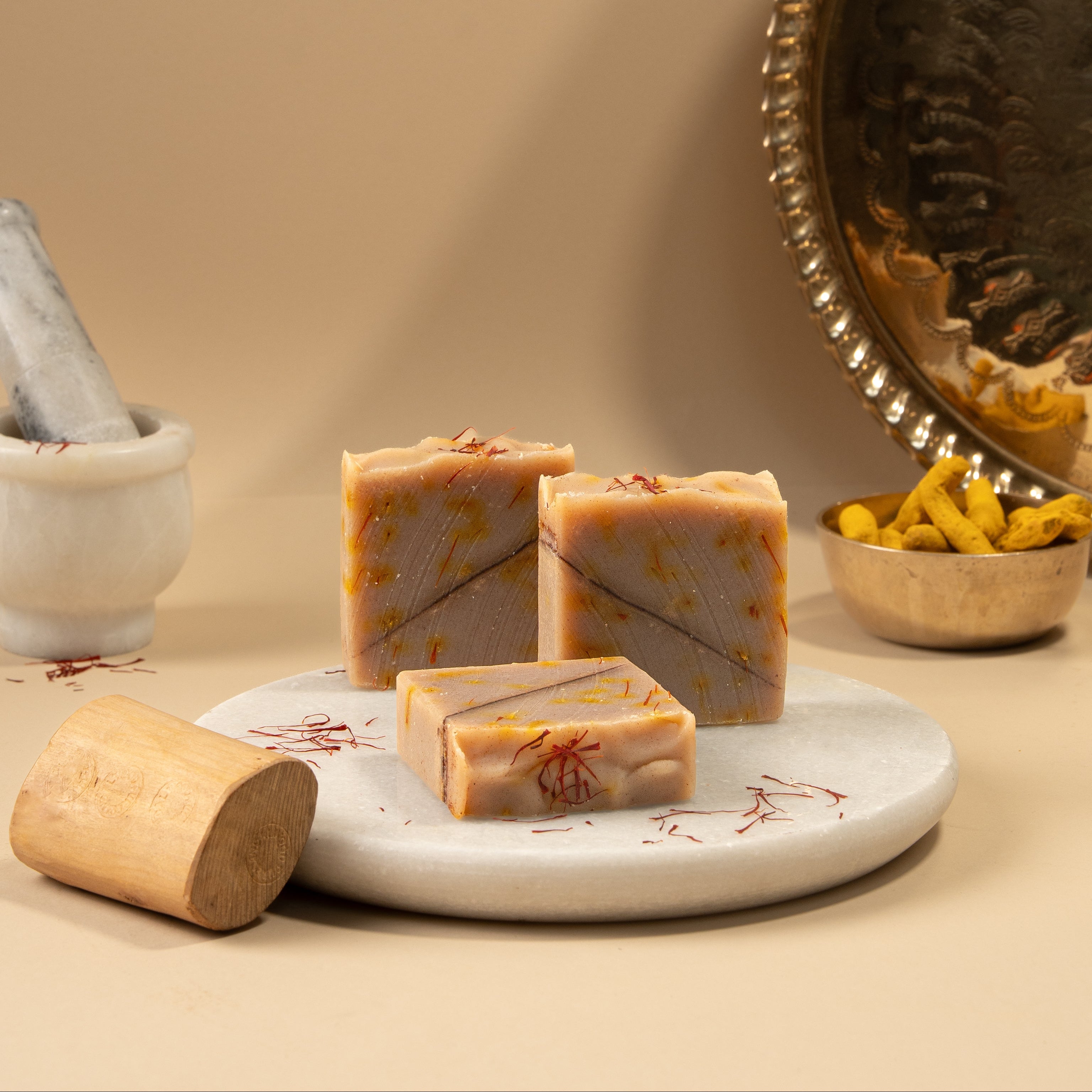 Three bars of soap on a white plate with a beige background