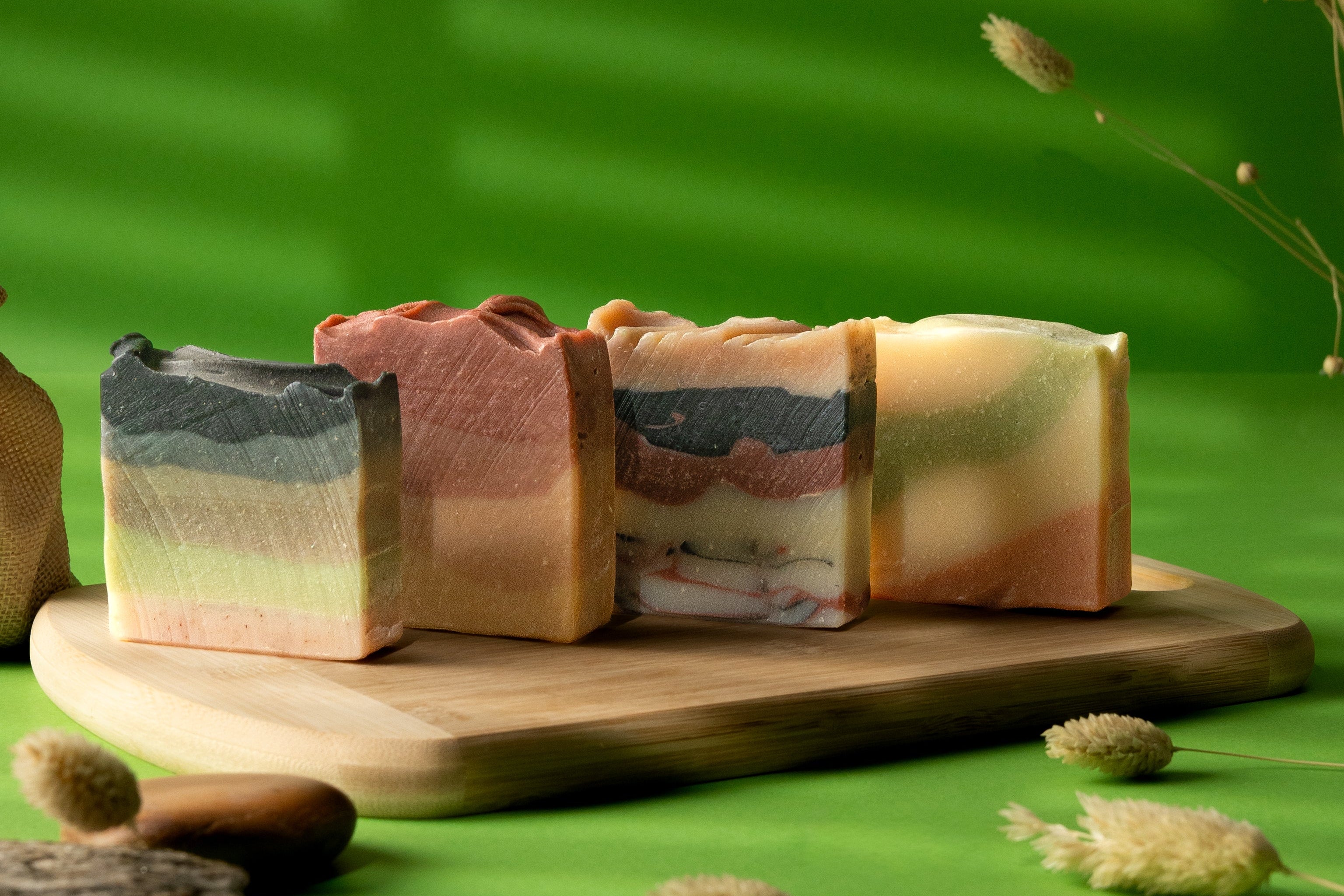 Three bars of soap on a wooden board with a green background