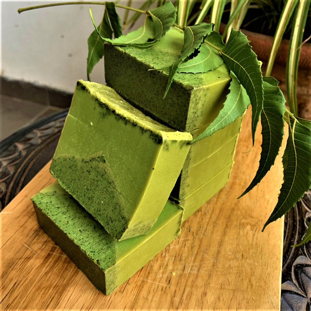 Stack of green soap bars on a wooden surface with leaves in the background
