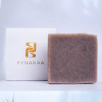 Bar of soap with a Fynakaa box on a light blue background with dried palm leaves.