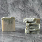 Three bars of green soap stacked on a gray marble surface with a gray marble background