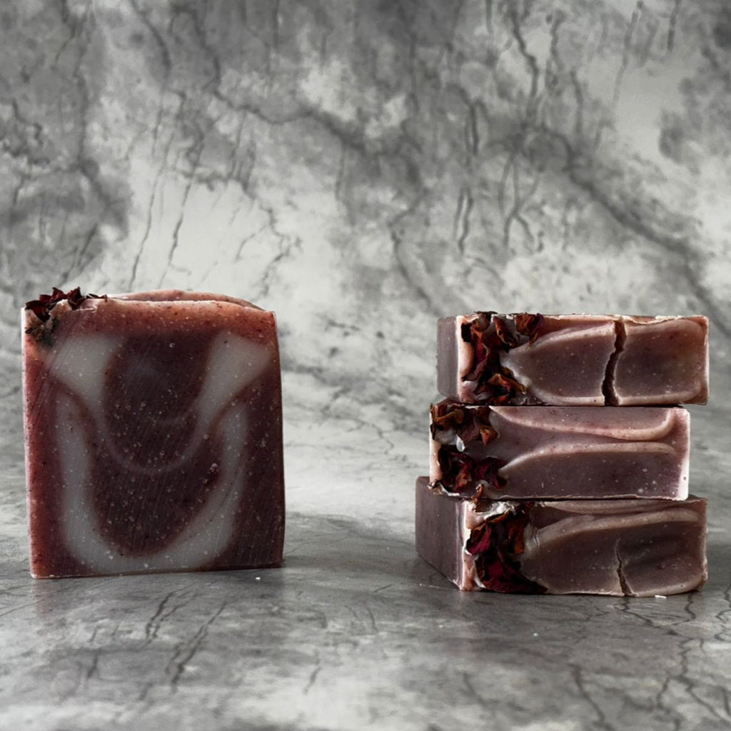 Handcrafted soap bars with a dark pin color and natural patterns, displayed on a textured background.