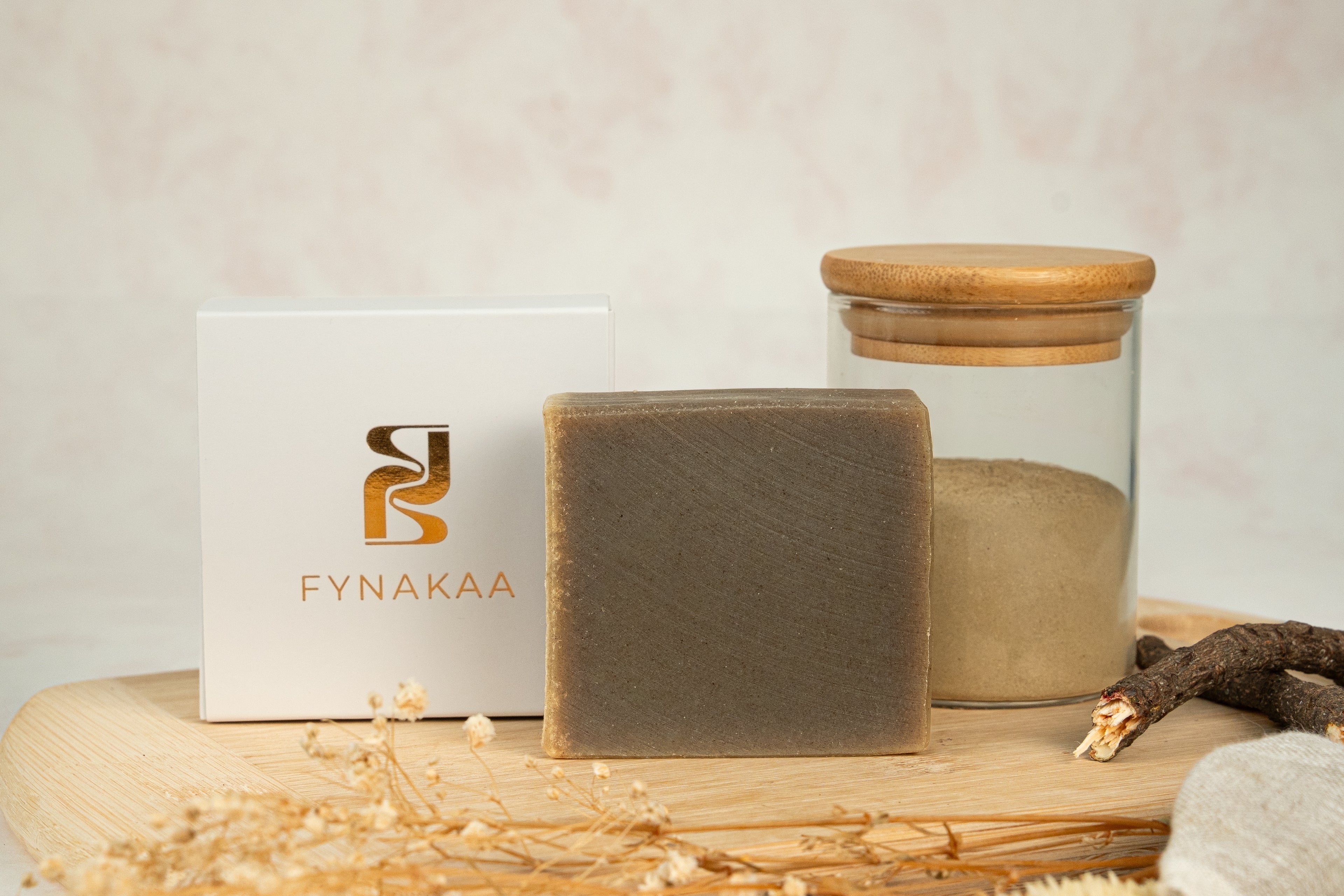 Bar of soap and glass jar with wooden lid on a wooden surface, Fynakaa brand visible