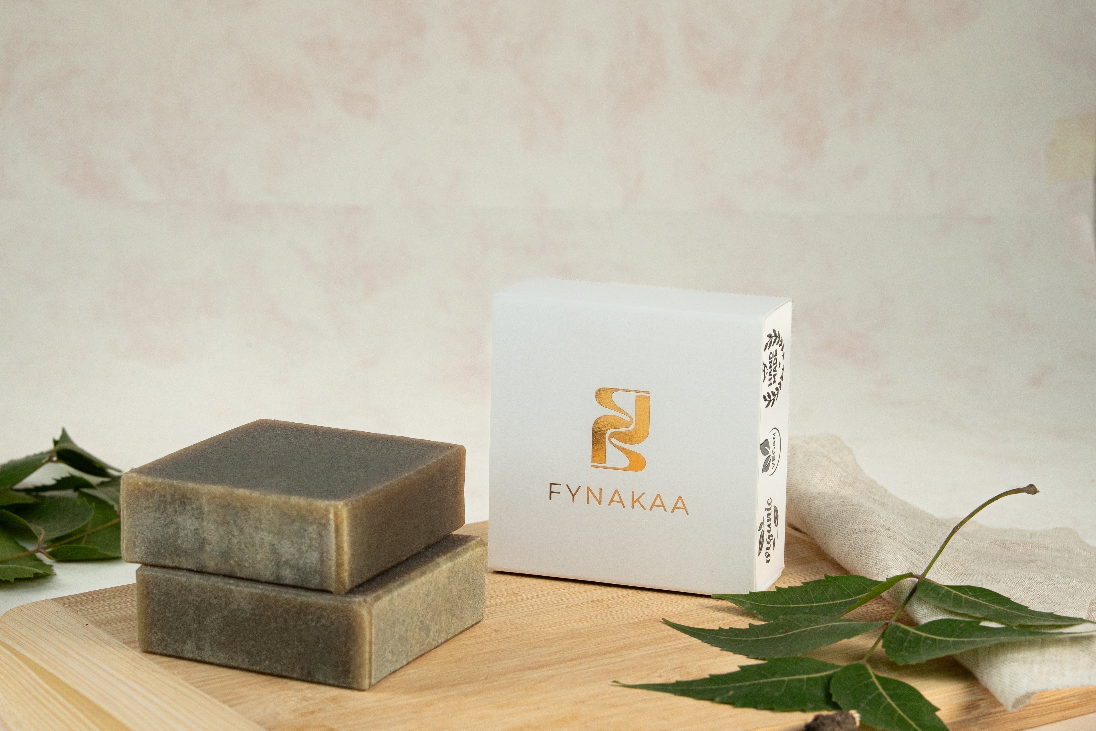 Two bars of soap on a wooden board with a Fynakaa box in the background.