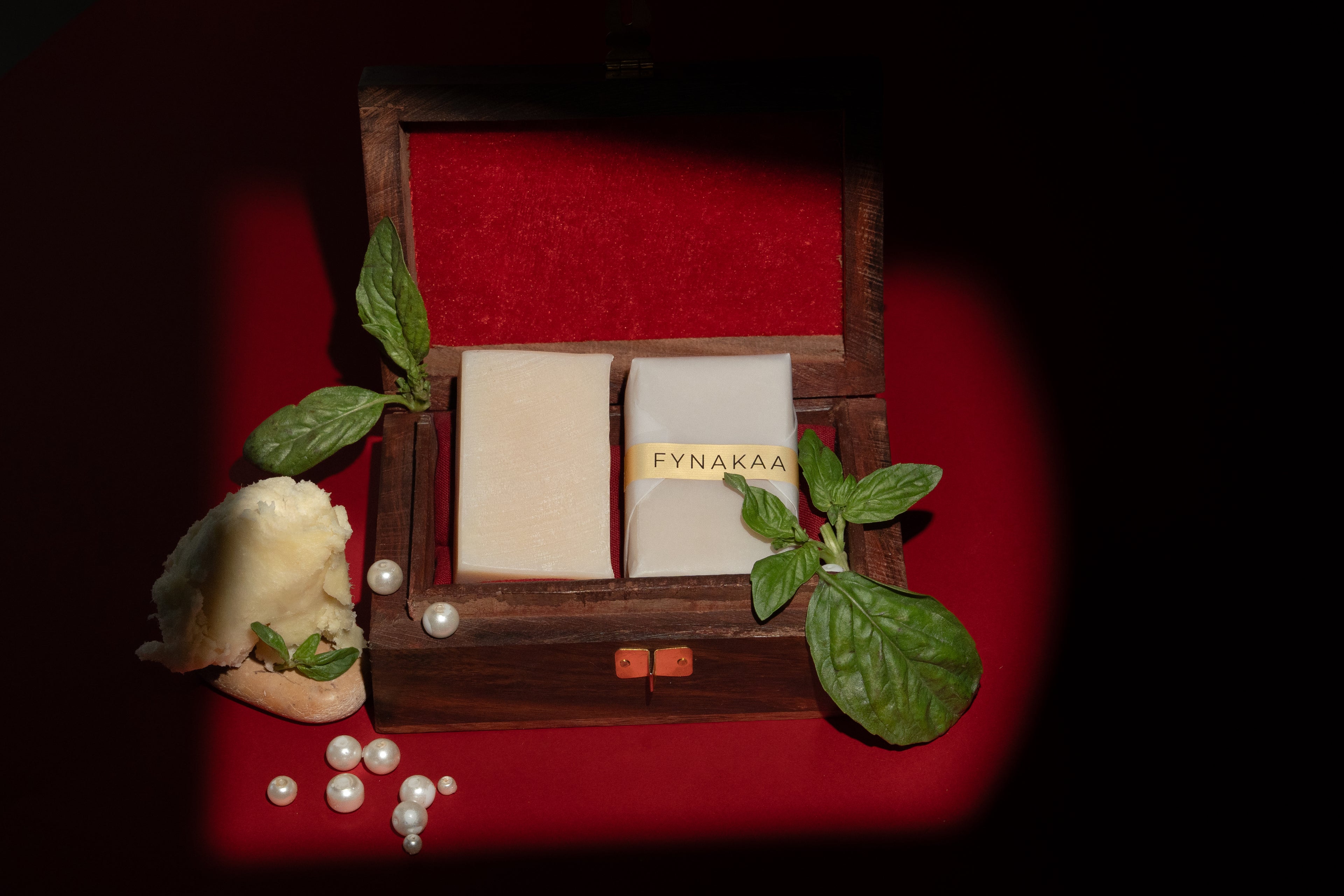 Two soap bars in a wooden box with decorative elements on a red background