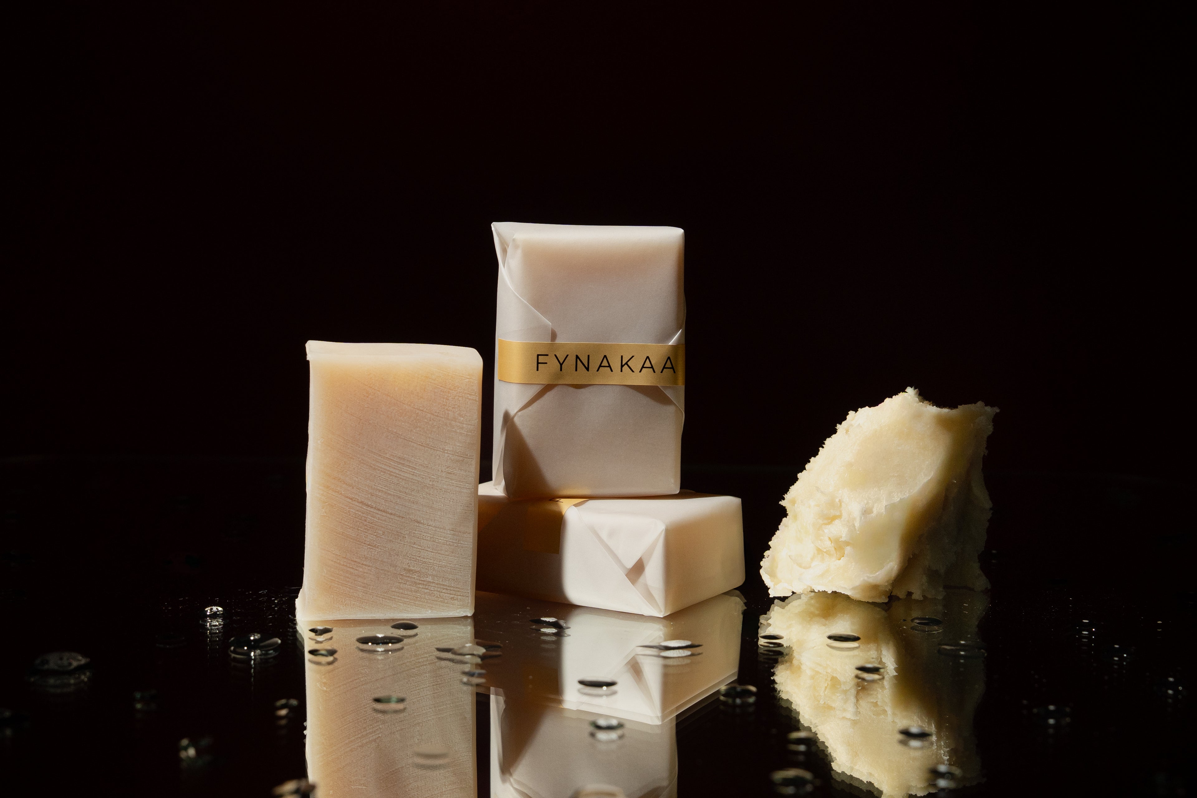 FYNAKAA soap bars and packaging on a reflective black surface