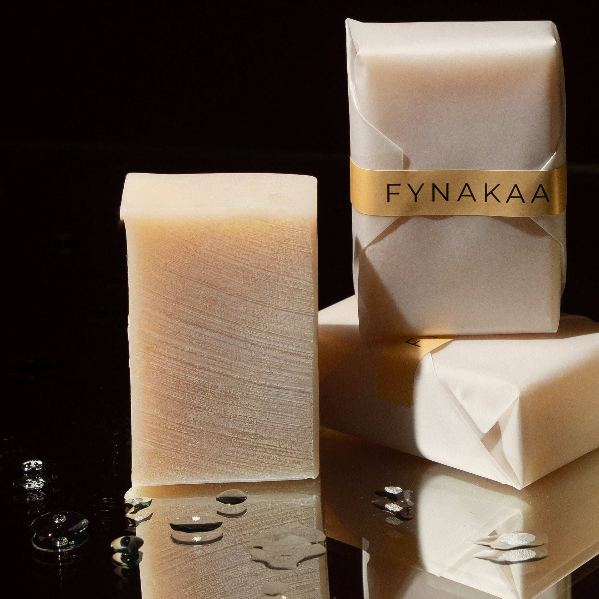 Fynakaa soap bars on a reflective surface with a dark background